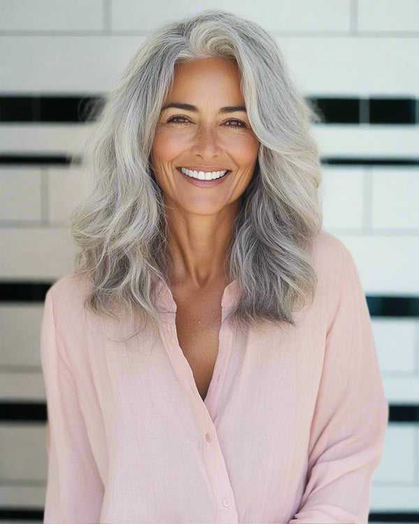 Woman with gray hair wearing a light pink shirt against a white background